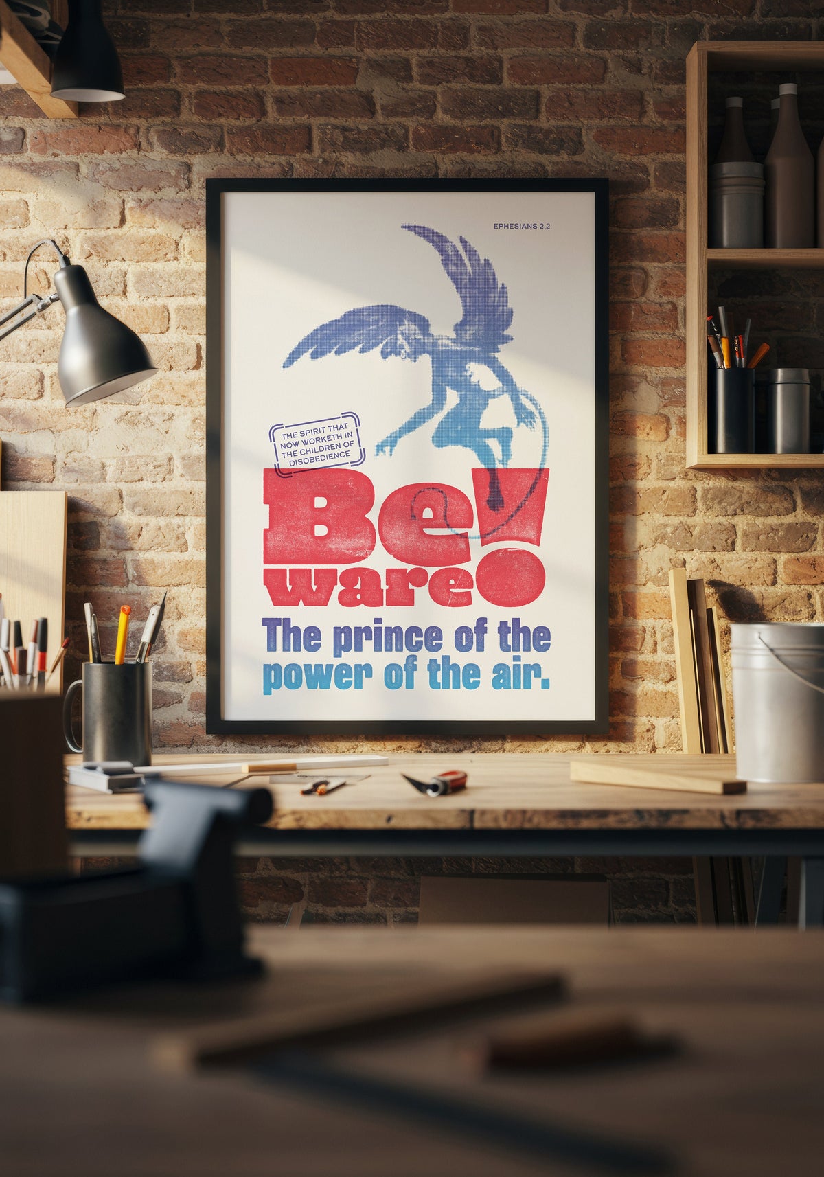 Ephesians 2:2 art print in a black frame, displayed above a workbench in a warmly lit home workshop.