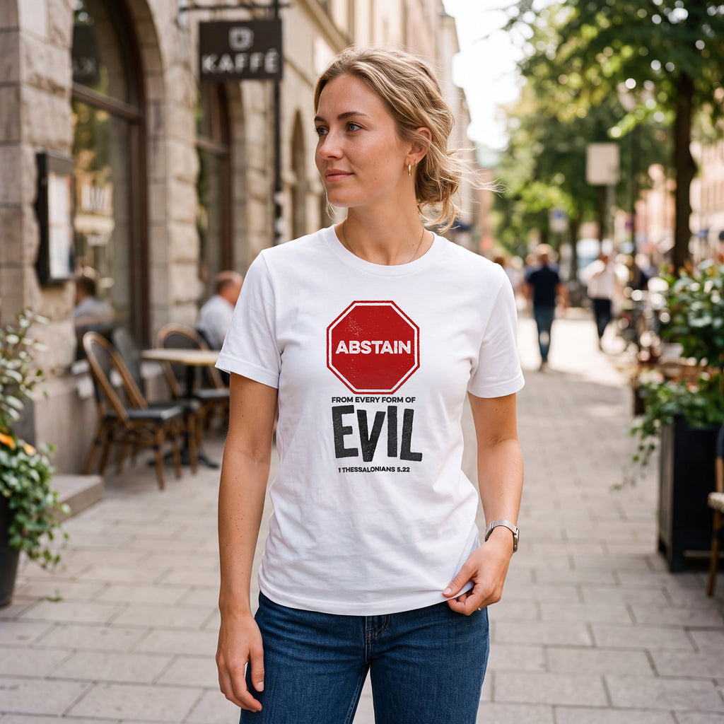 Woman on city sidewalk wearing white t-shirt with 1 Thessalonians 5.22 graphic print.