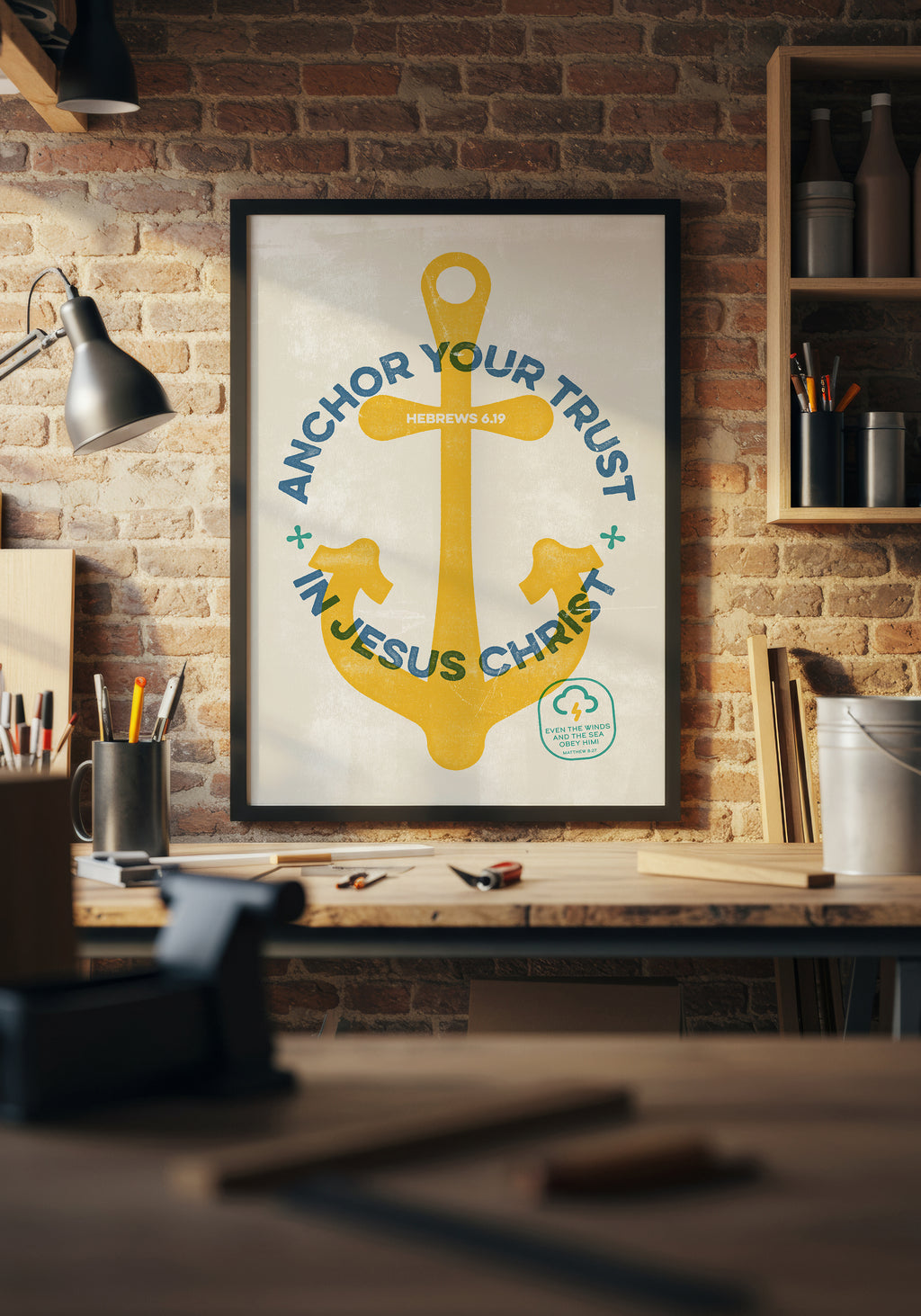 Hebrews 6:19 print in a black frame, styled above a workbench in a sunlit home workshop.