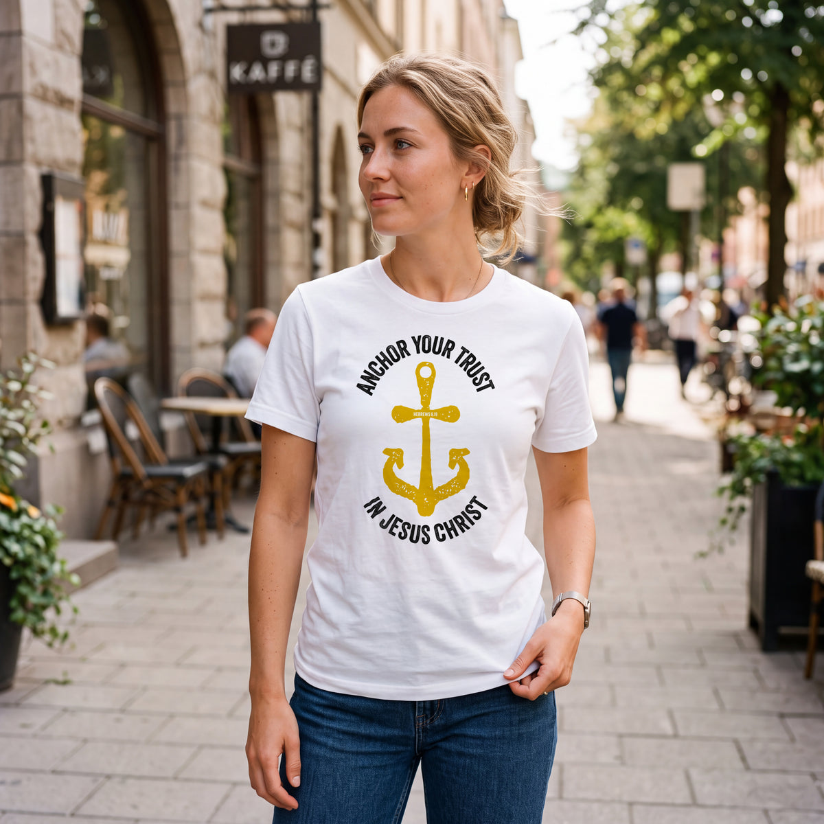 Woman on city sidewalk wearing white t-shirt with Hebrews 6.19 graphic print.