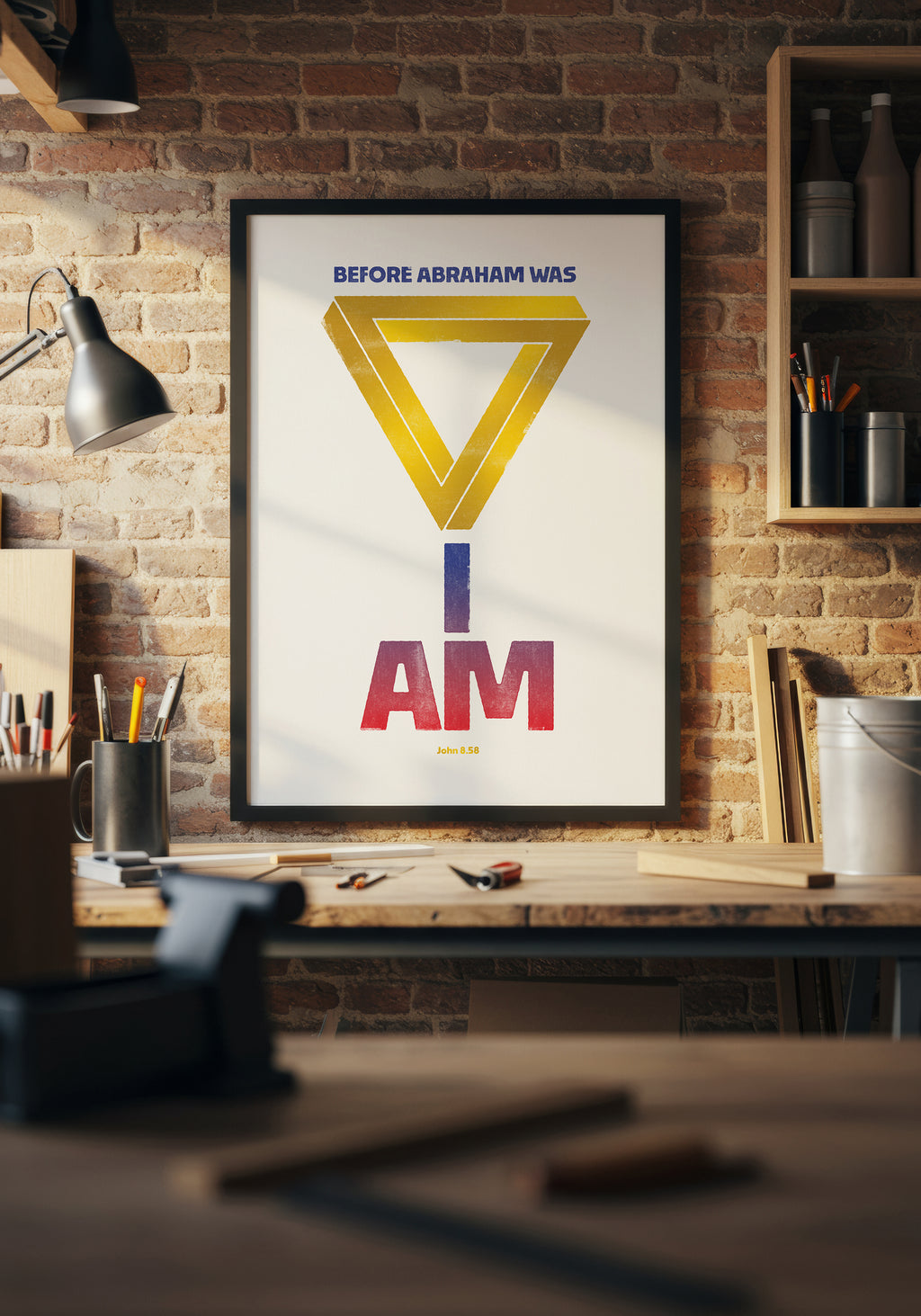 John 8:58 print in a black frame, styled above a home workshop workbench in a beam of natural light.