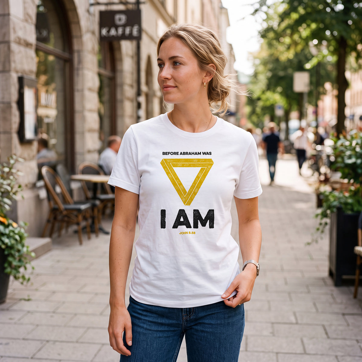 Woman on city sidewalk wearing white t-shirt with John 8.58 graphic print.