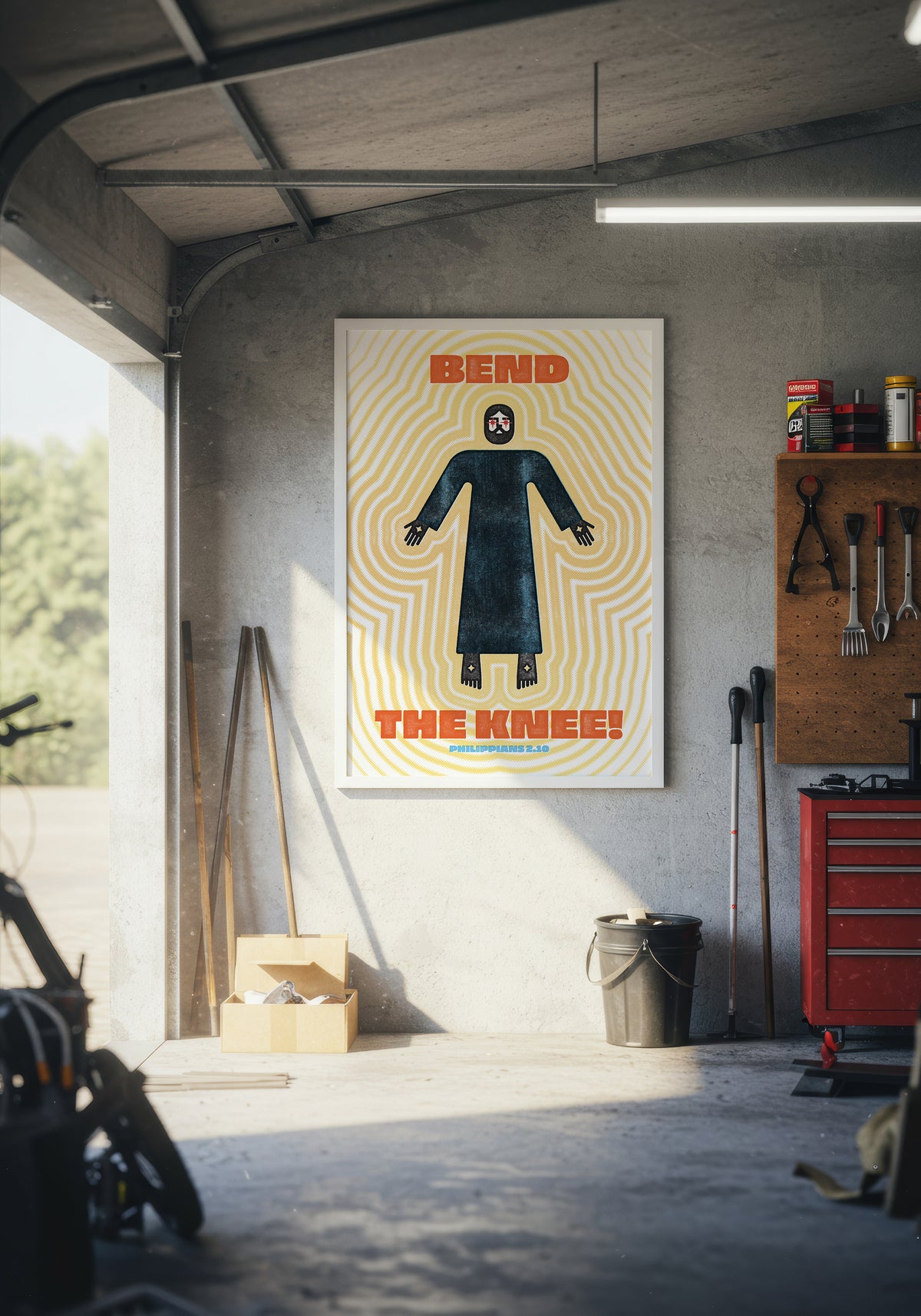 Philippians 2:10 art print displayed in a white frame on a wall inside a modern, warmly lit garage.