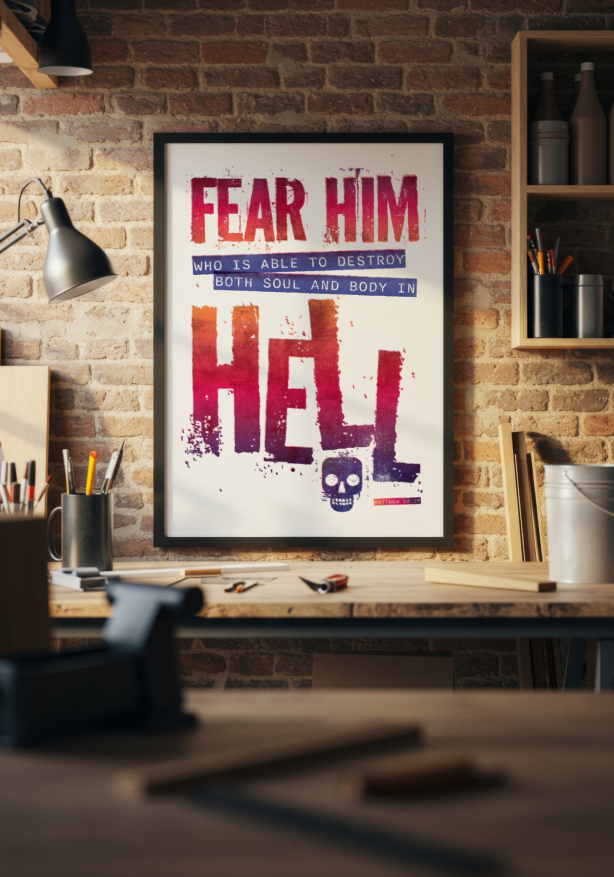 Matthew 10:28 print in a black frame, lit by natural sunlight above a workbench in a home workshop.