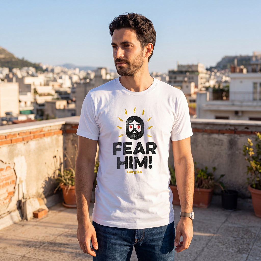 Man standing on a rooftop terrace with a cityscape background, wearing a white t-shirt with Luke 12:5 graphic printed on the front.