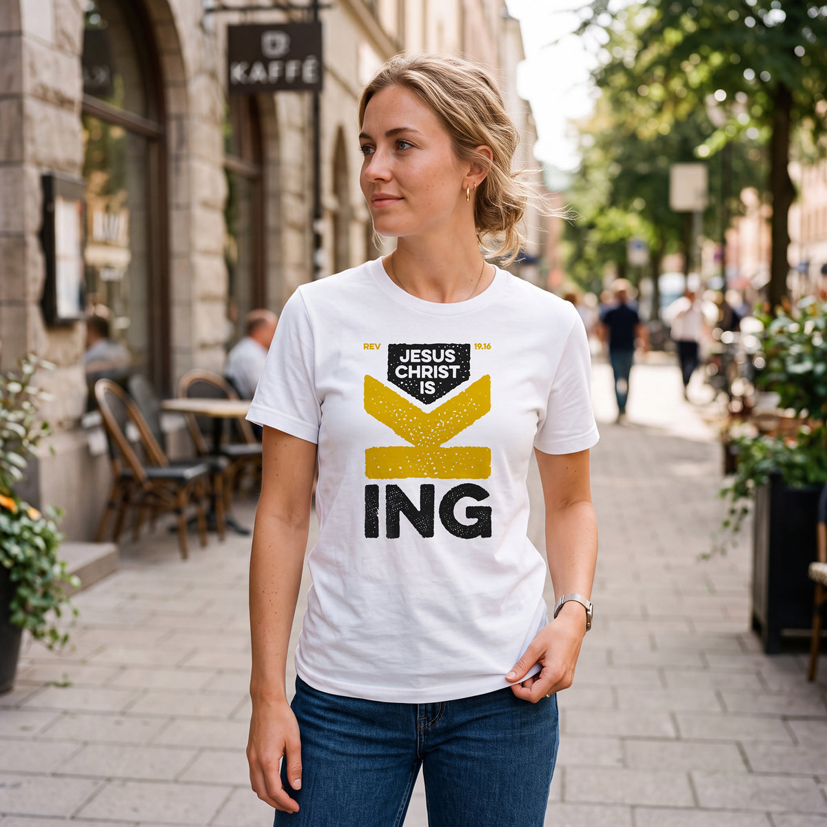 Woman on city sidewalk wearing white
t-shirt with Revelation 19.16 graphic print.