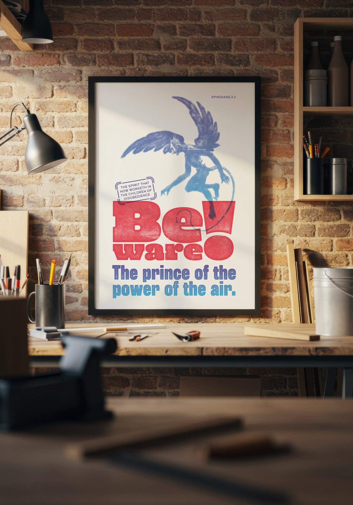 Ephesians 2:2 art print in a black frame, displayed above a workbench in a warmly lit home workshop.