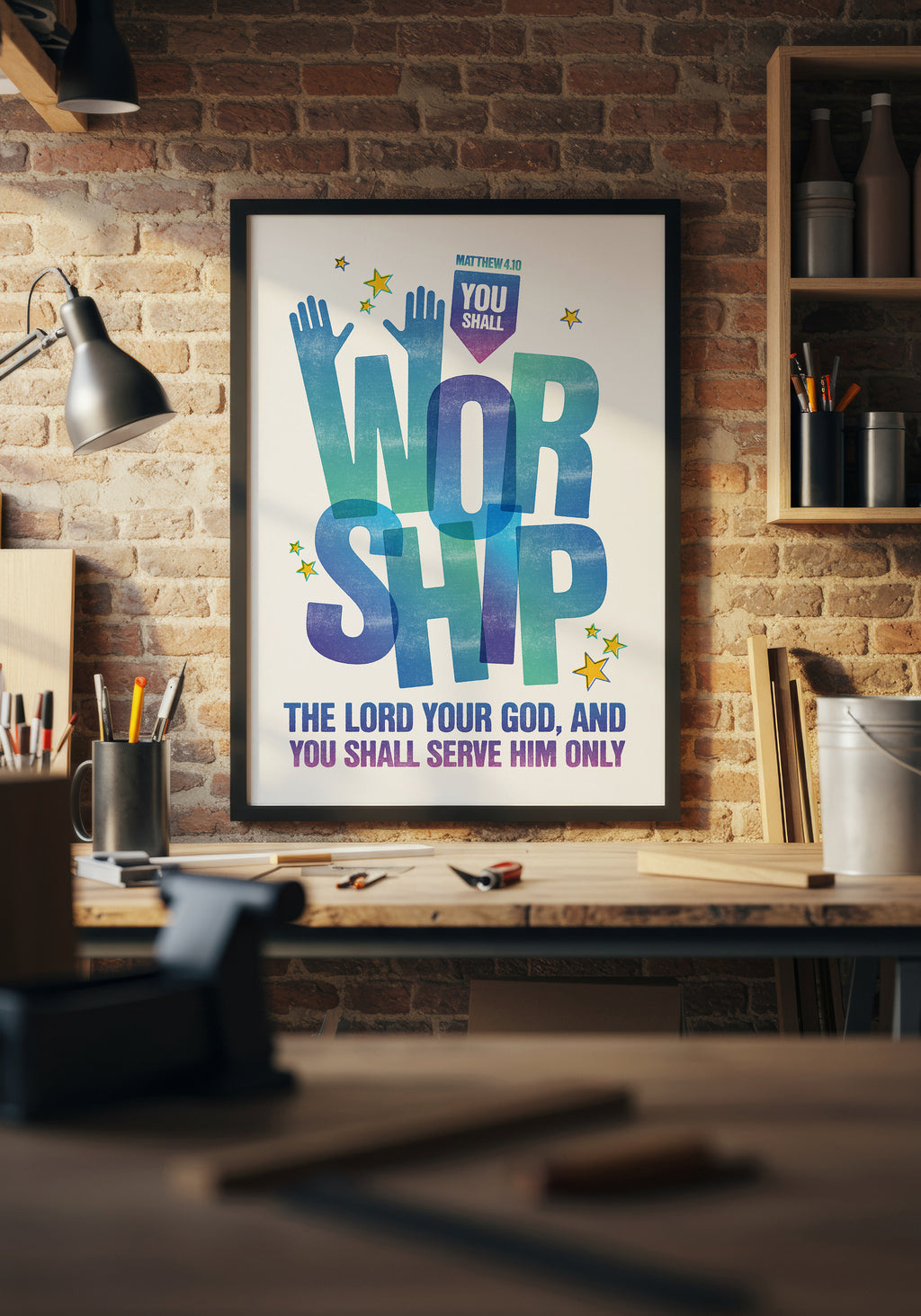 Matthew 4:10 scripture art print in a black frame, displayed above a workbench in a warmly lit home workshop.