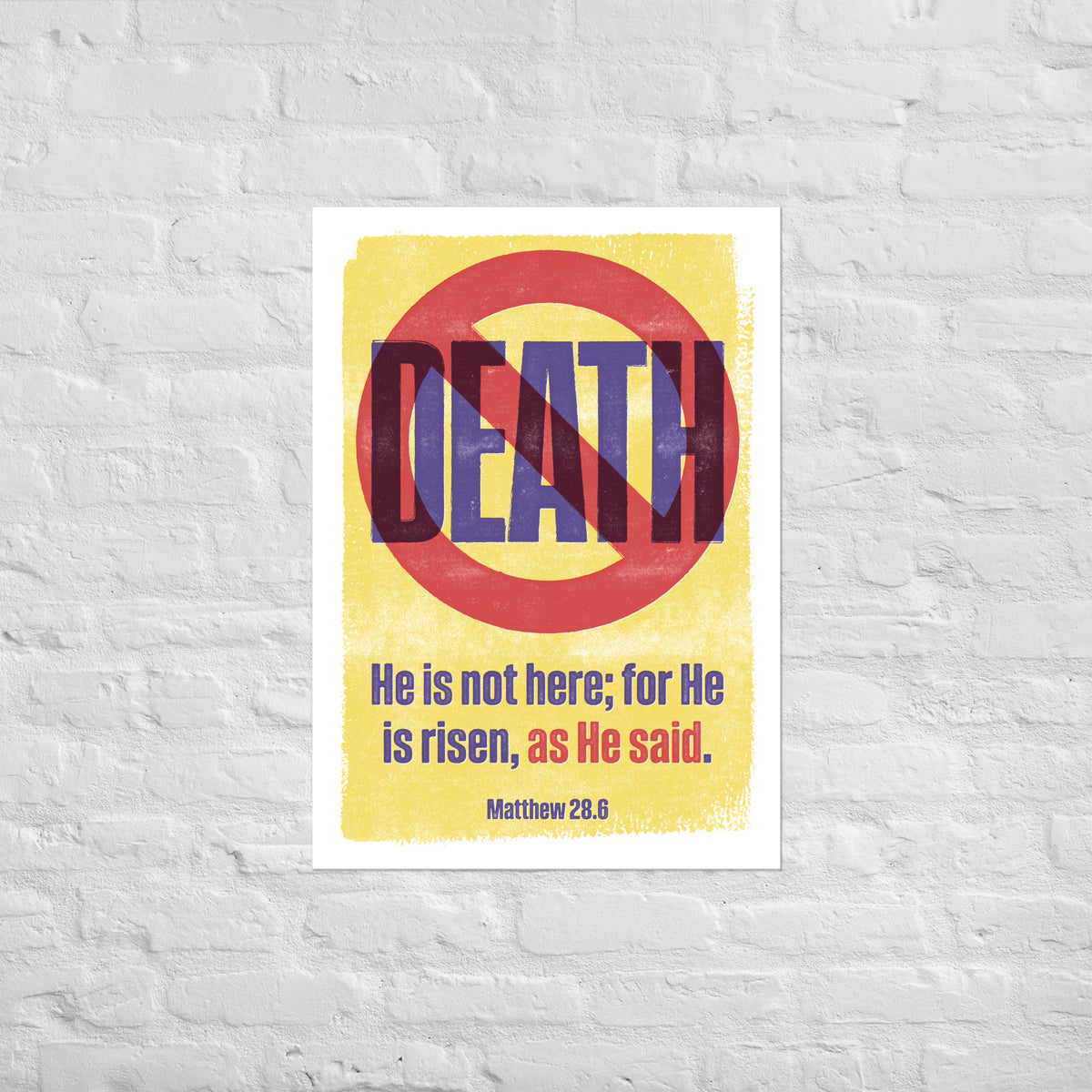Matthew 28:6 print mounted directly on a white brick wall for a frameless, modern look.